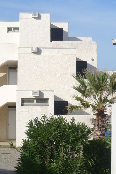 Logements collectifs. Détail des acrotères, finement soulignés par une rainure dans le béton et système de rejet d'eau, donnant un aspect très graphique aux façades.