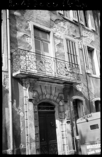 Façade sur rue ; portail et balcon en fer forgé le surmontant.