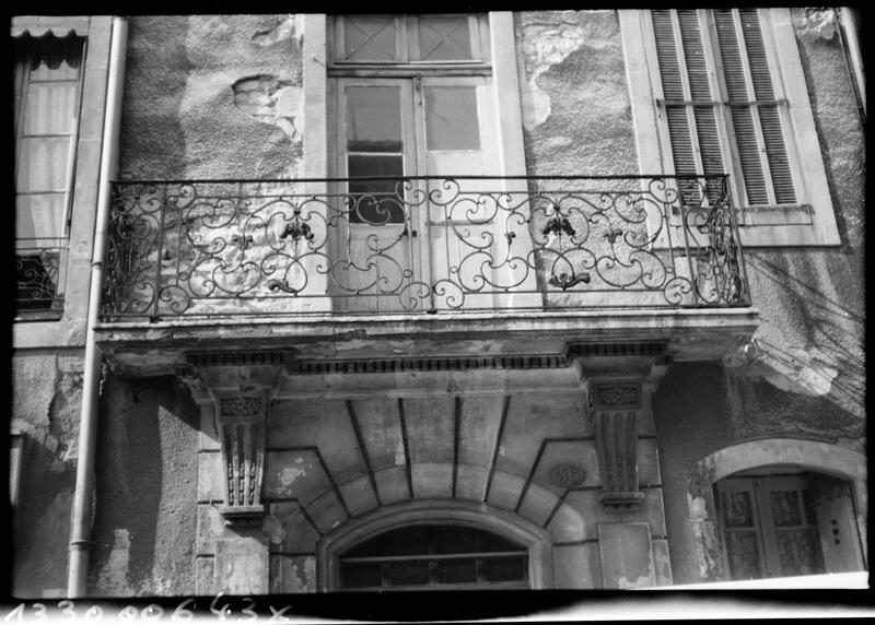 Façade sur rue ; arc du portail et balcon en fer forgé le surmontant.