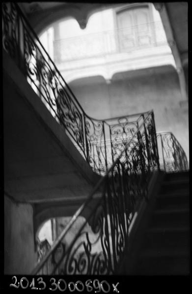 Cage d'escalier avec rampe en fer forgé.