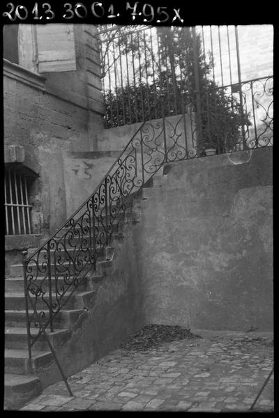 Rampe en fer forgé de l'escalier extérieur entre cour et jardin et grille du jardin.