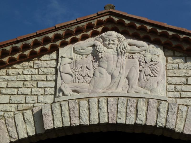 Façade de la cave d'origine : motif sculpté par Armand Pellier sur le fronton de l'auvent en pierre et représentant Dyonisos.