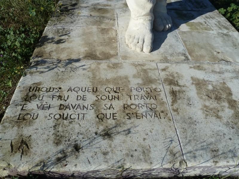 Statue de porteur sculptée par Armand Pellier et déplacée en 2007 devant le caveau d'Héraclès construit sur la R.N. 113 ; détail de l'inscription "urous aqueu que porto lou fru de soun travai et vei davans sa porto lou soucit que s'en vai".