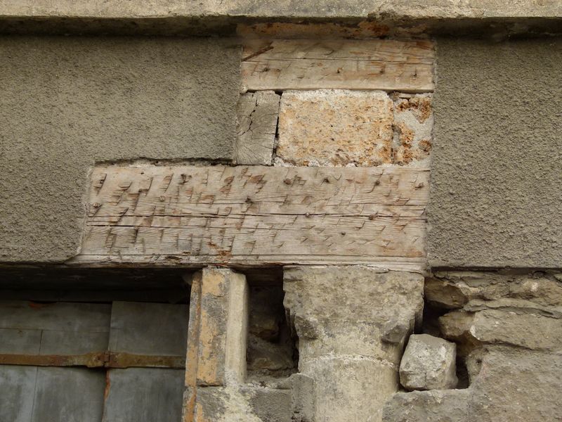 Façade principale. A droite de la porte apparaît une colonne à chapiteau provenant de la construction précédente. Détail du linteau en bois et pierre.