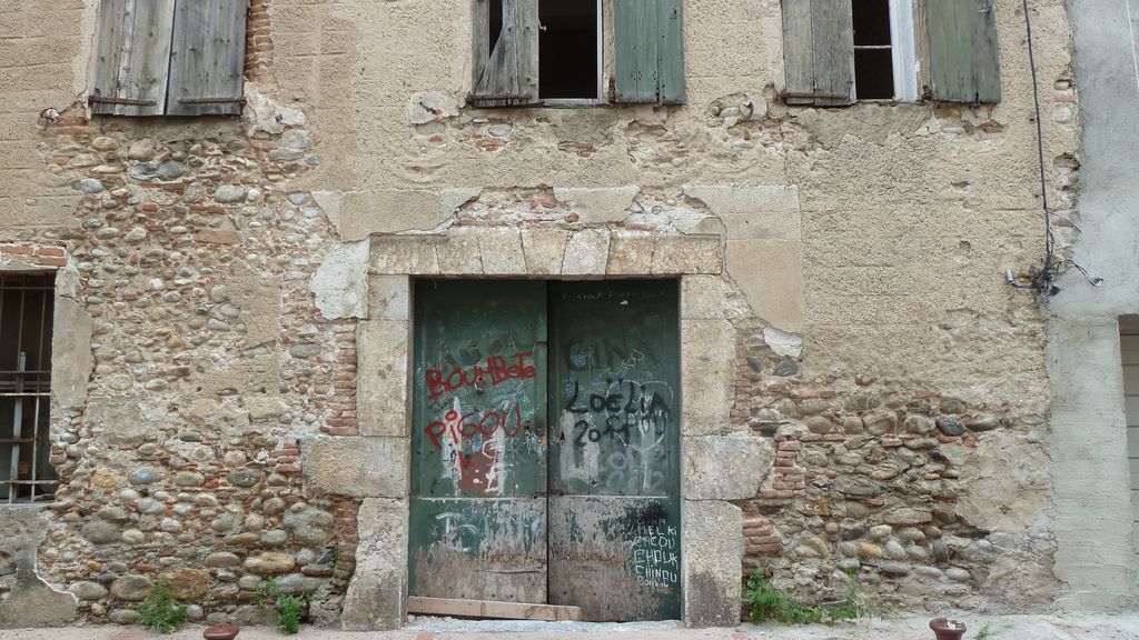 Façade sur la rue construite en briques et galets et couverte d’un enduit à faux refends.