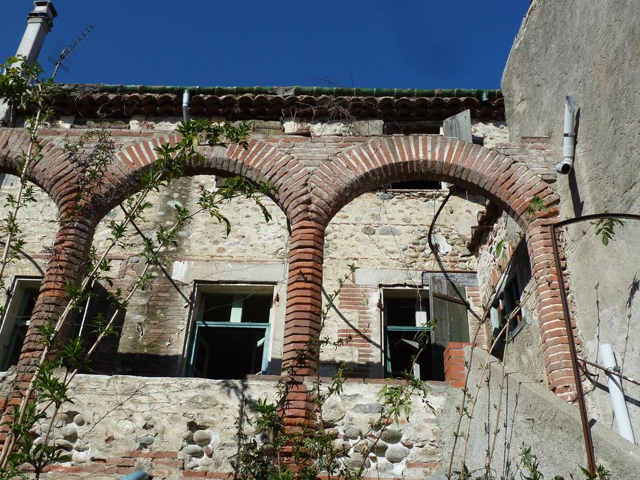 Cour intérieure. Façade sud. Galerie. Série d'arcs en plein cintre en briques.