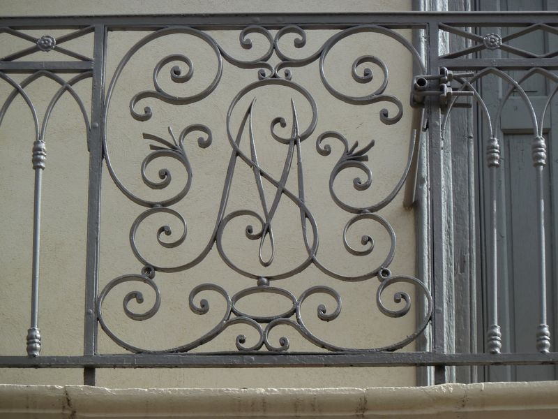 Façade à deux travées ornée d'un balcon. Détail de la ferronnerie. Initiales SM pour Saury Mons.