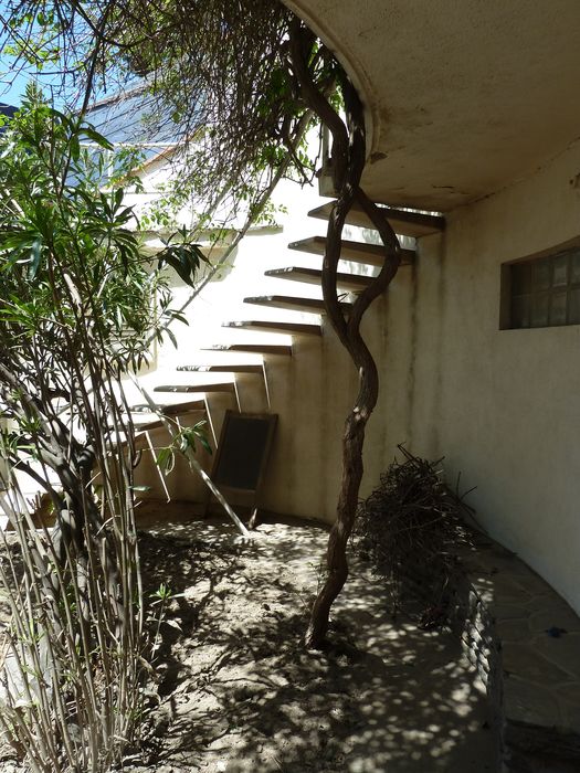 Façade arrière. L’espace protégé du soleil par le balcon et l’escalier est animé par un banc en schiste.