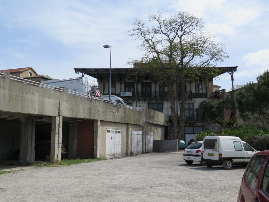 Vue de la façade principale, depuis le jardin de la distillerie Sabatier, partiellement occupé le long de l’avenue par un bâtiment de garages.