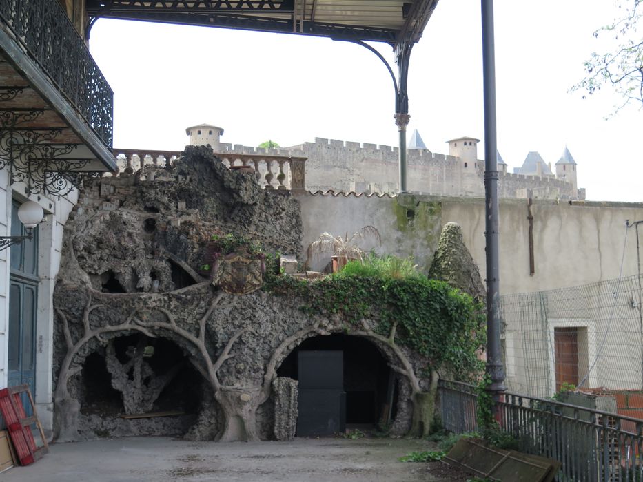 Terrasse. Contre le mur sud s’appuie une grotte en rocaille. En arrière-plan, la vue sur la Cité de Carcassonne.