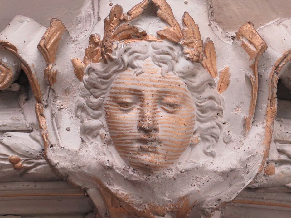 Salle des fêtes du 1er étage. Décor du plafond. Détail d'une tête en stuc dorée.