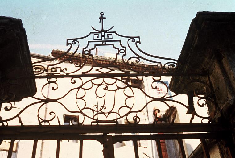 Façade ouest, portail ouvrant sur la cour, couronnement en ferronnerie portant le monogramme de Godefroy de Jonc.