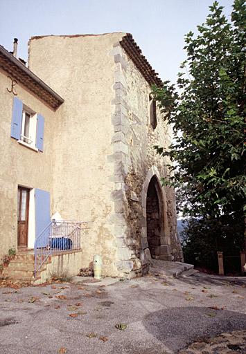 Place du village, façade sud de l'ancienne porte de ville avec grand arc brisé.