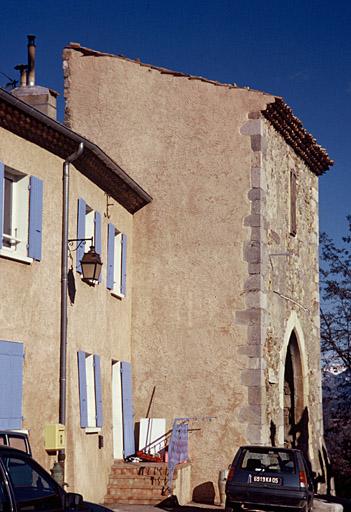 Place du village, façade sud de l'ancienne porte de ville avec grand arc brisé.