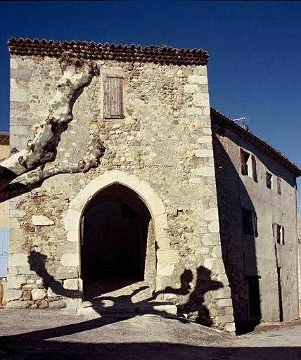 Place du village, façade sud de l'ancienne porte de ville avec grand arc brisé.