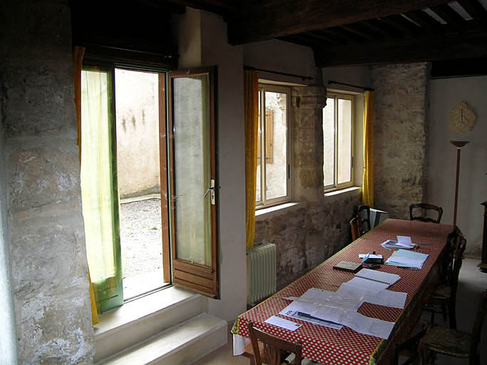 Vue de la salle au rez-de-chaussée donnant sur la cour intérieure, pilier central d'un ancien préau.