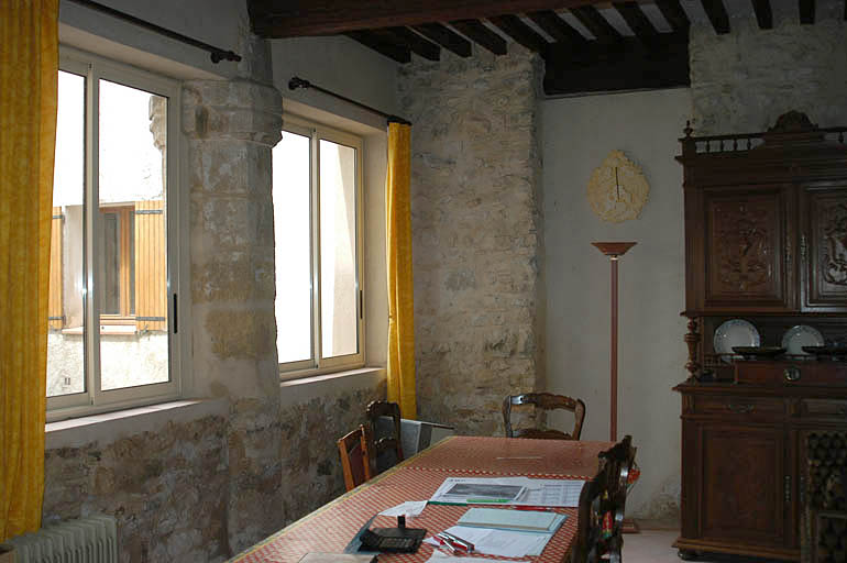 Vue de la salle au rez-de-chaussée donnant sur la cour intérieure, pilier central d'un ancien préau.