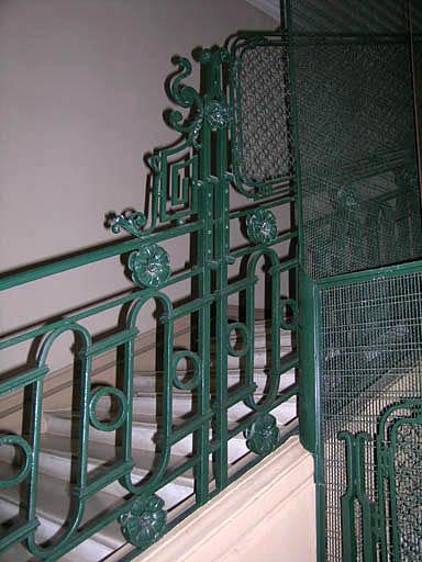 Cage d'escalier, détail sur rampe en fer forgé ouvragée.