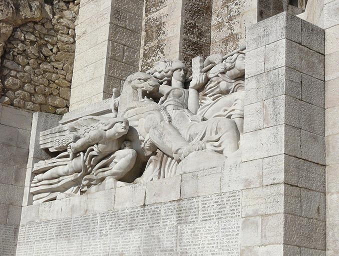 Façade du monument, partie gauche, haut-relief et noms des victimes, vue de trois-quarts.