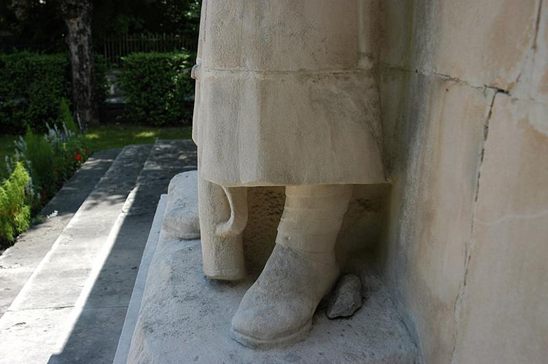 Vue du chasseur alpin de profil, il porte de grosses chaussures avec les bandes molletières, la crosse du fusil à terre.