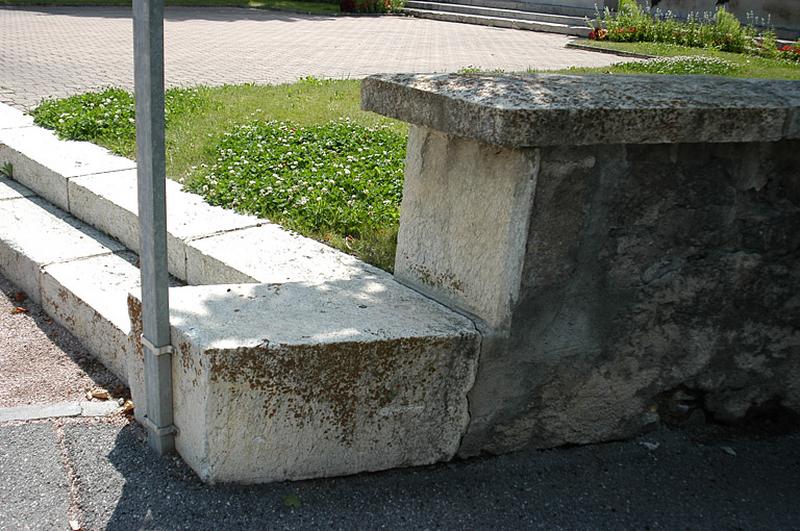 Vue de l'aménagement autour du monument, un podium bordé d'un muret et surélevé de deux marches.