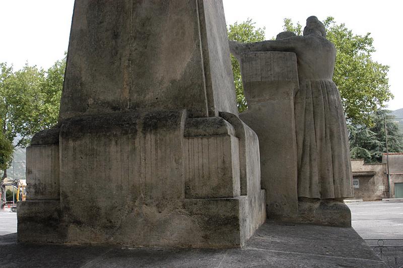 Vue de la face postérieure du monument, la femme est vue de dos, elle porte une longue robe qui descend jusqu'aux chevilles.