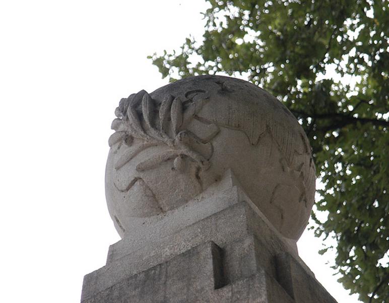 Vue de la partie supérieure de l'obélisque, ornée d'un globe terrestre avec, en relief, une branche d'olivier, symbole de paix, posée sur une partie du monde.