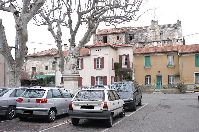 Vue générale de la place des Poilus, à l'arrière plan les parties hautes du château. Le soldat est tourné vers le château.