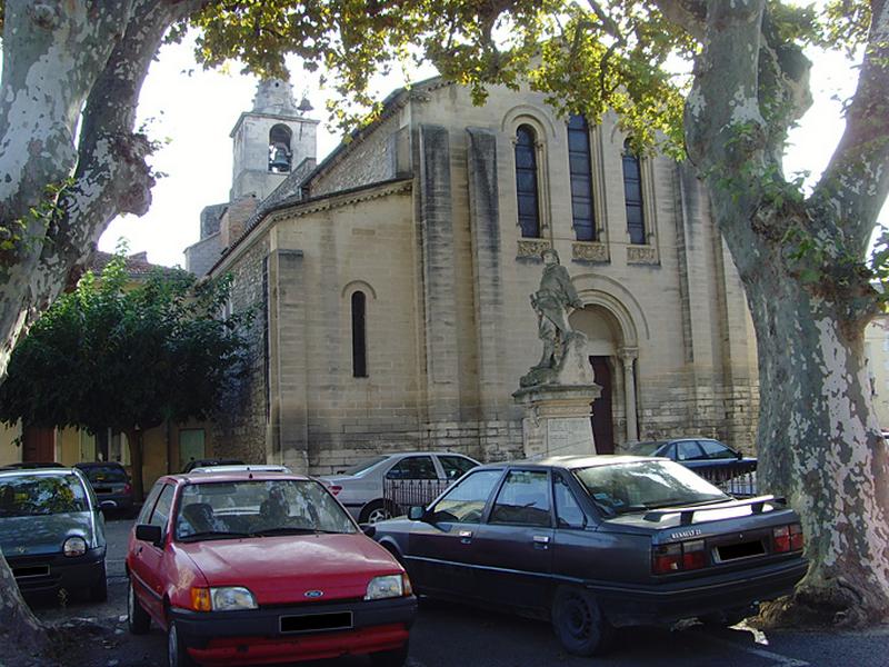 Vue générale de la place des Poilus, à l'arrière plan la façade de l'église paroissiale. Le soldat tourne le dos à l'église.