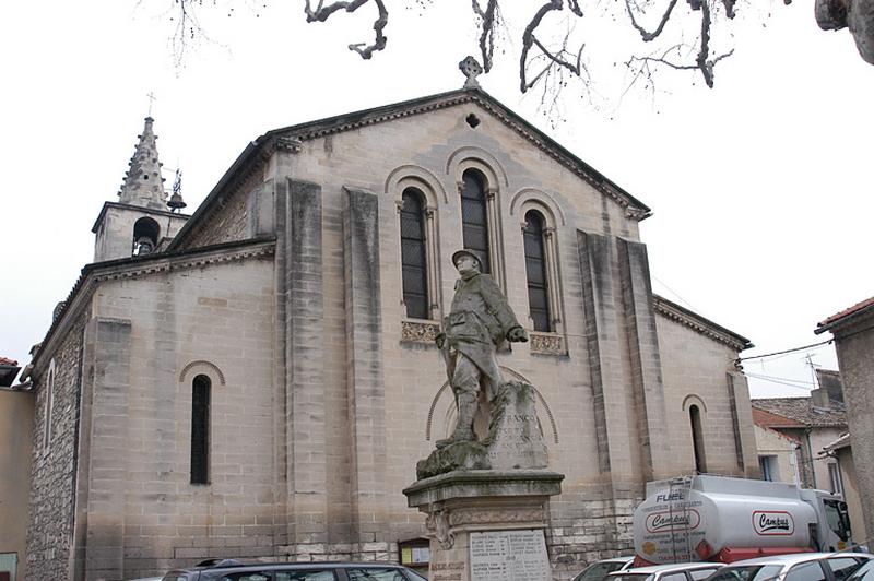 Vue générale de la place des Poilus, à l'arrière plan la façade de l'église paroissiale. Le soldat tourne le dos à l'église.