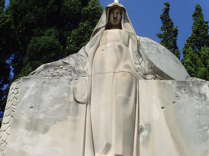 Vue de la statue féminine représentant l'allégorie de la France. Voilée, elle porte un bouclier sur l'avant bras gauche; elle est appuyée contre un massif rectangulaire, les bras étendus au-dessus de deux chutes de laurier qui s'écoulent sur les bords du massif.