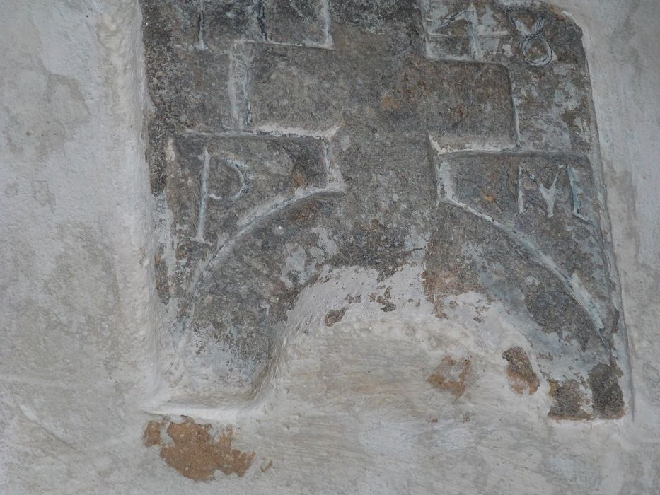 détail d’un bas-relief : Croix au-dessus d’un demi-cercle encadrée des lettres P et M