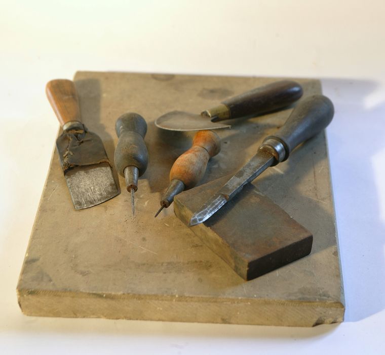 Pierre à parer avec ensemble pour apprêter les peaux avant encollage (trois couteaux à parer, deux poinçons à piquer)