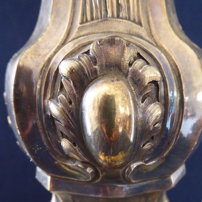 Ostensoir-soleil, cartouche constitué de feuillages et contenant au centre un médaillon ovale, lisse et convexe au départ de la tige.