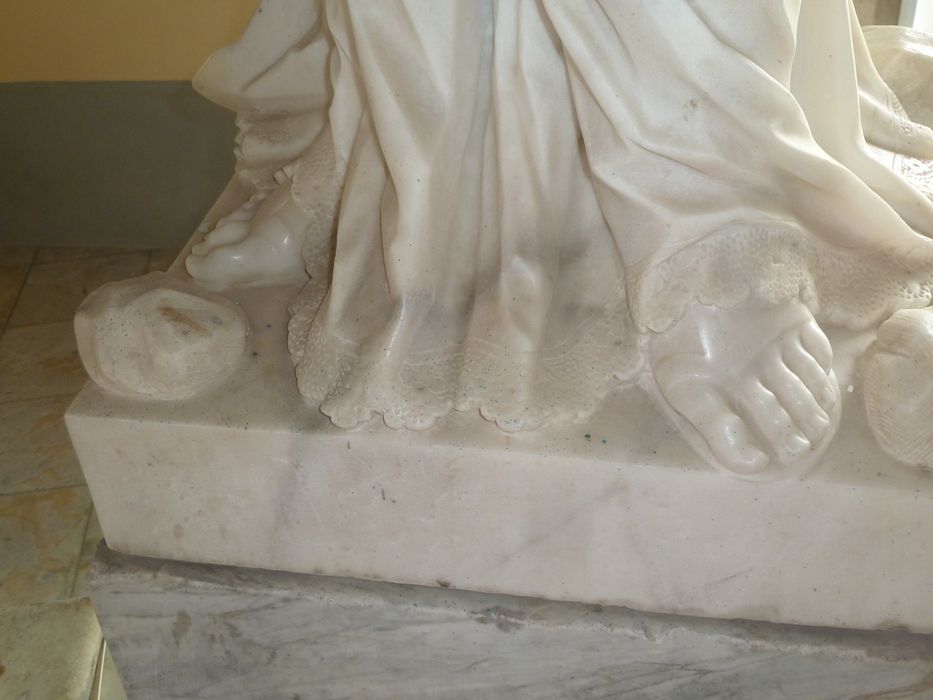 Statue de Saint Étienne : détail de la dentelle qui orne la partie inférieure de l’aube et des pierres posées à ses pieds en référence à sa lapidation.