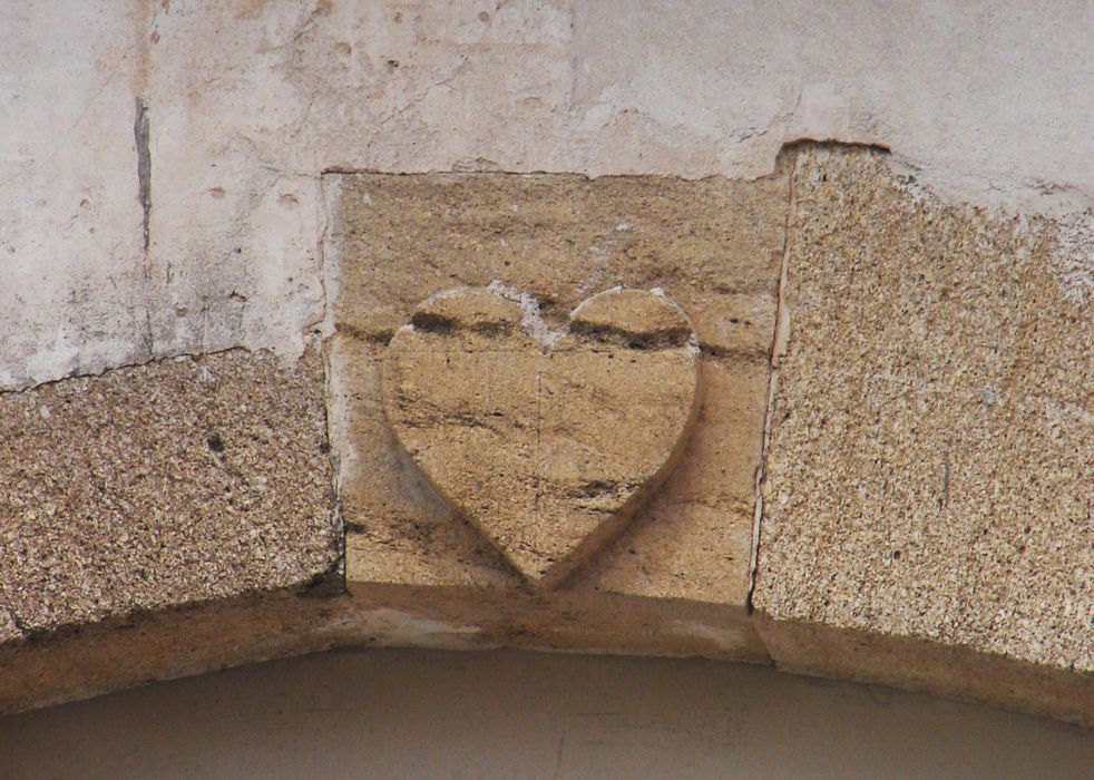 Église. Transept sud (élévation ouest) : cœur sculpté sur la clé de l’arc segmentaire de la fenêtre.